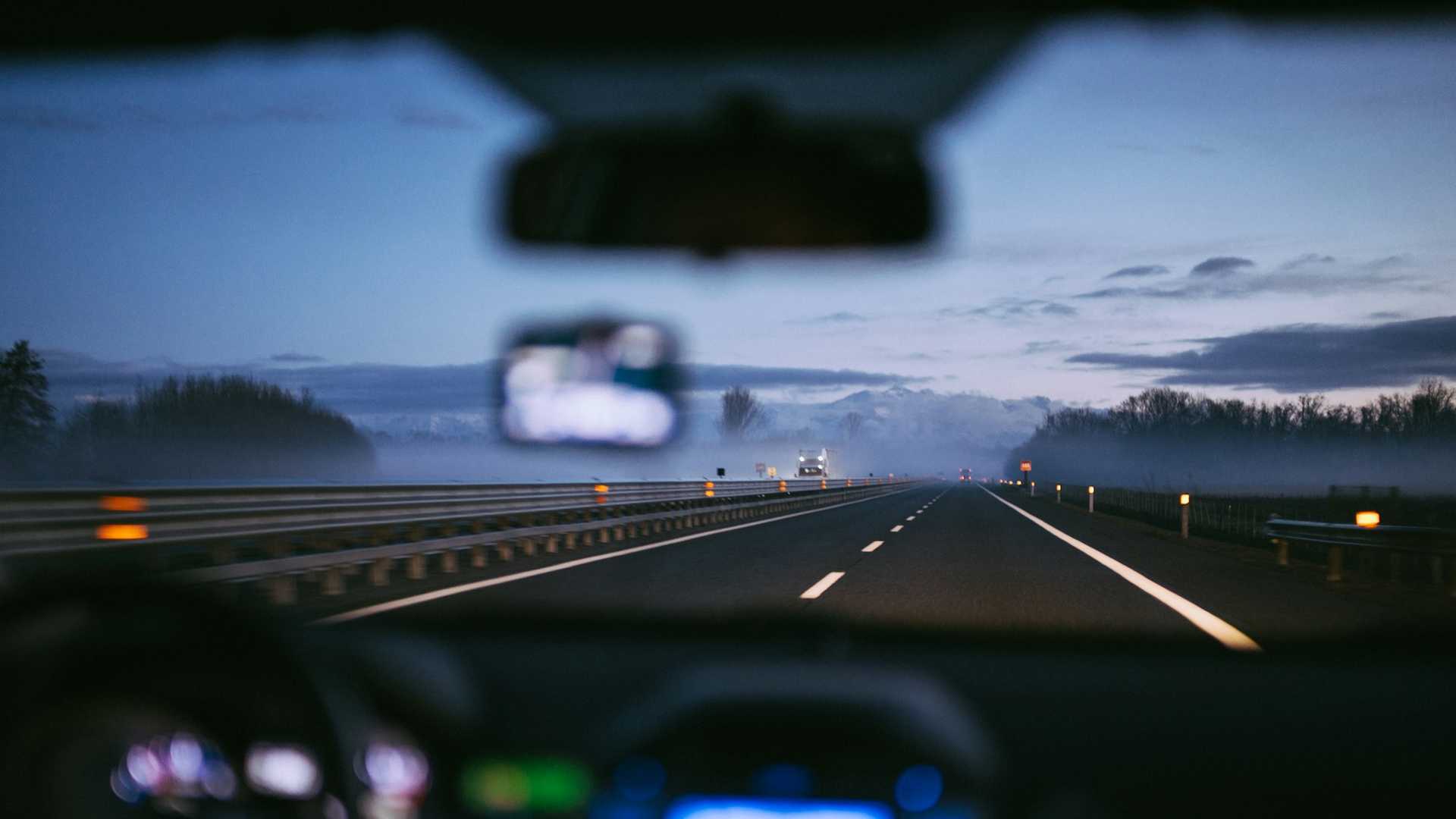 Vista da estrada à noite através do para-brisa de um carro em movimento