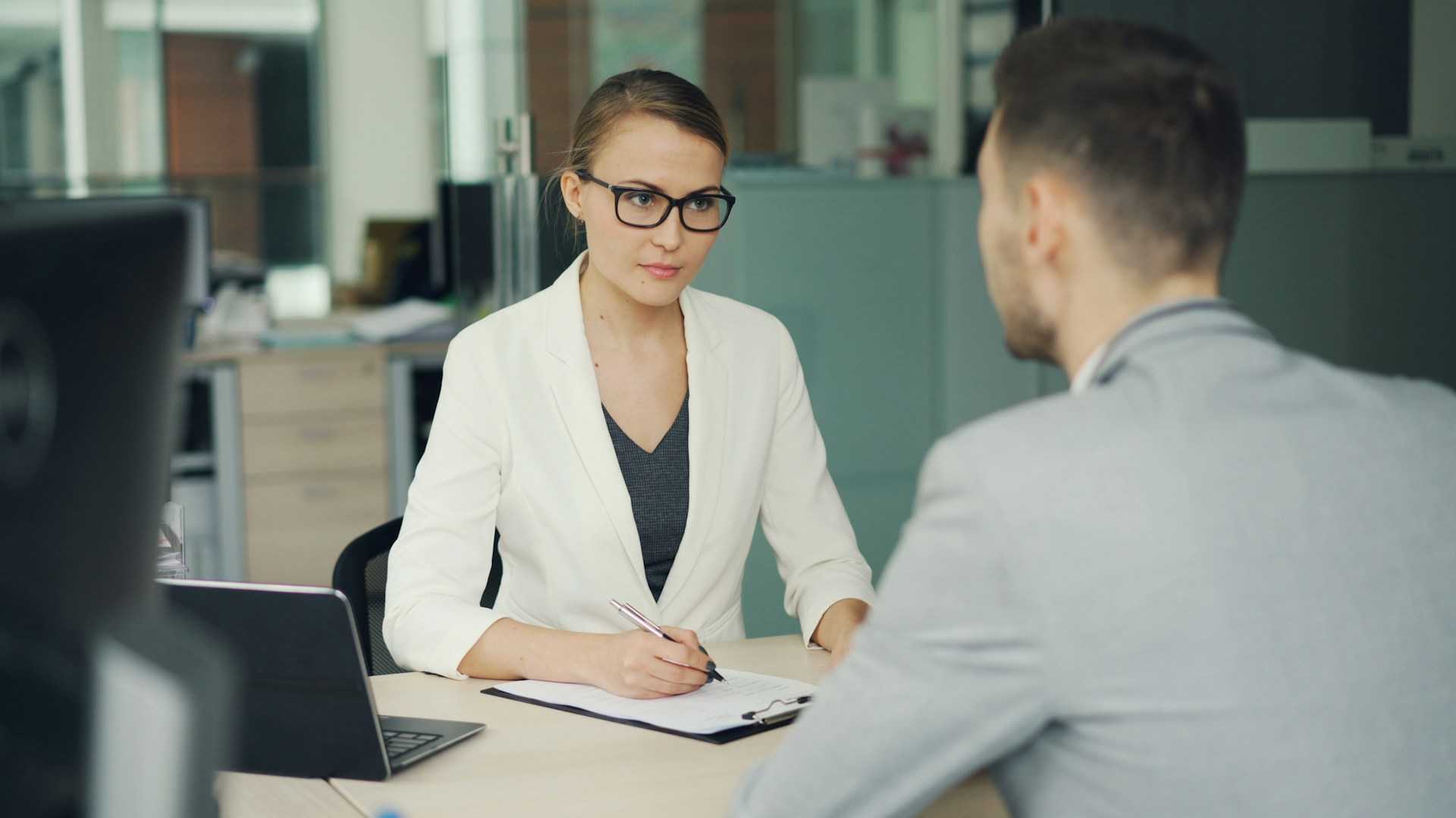 Recrutadora conduz entrevista com um candidato em uma mesa de escritório: a verificação completa só com os finalistas evita atrasar o processo seletivo. Foto: Vitaly Gariev, Unsplash
